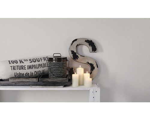 Dekoratívna scéna s vankúšom, plechovkou, sviečkami a objektom v tvare písmena S na polici