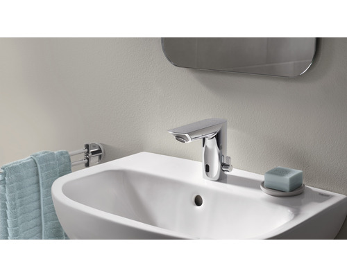 Fotografia kúpeľne s umývadlom, vodovodnou batériou, uterákom a zrkadlom.