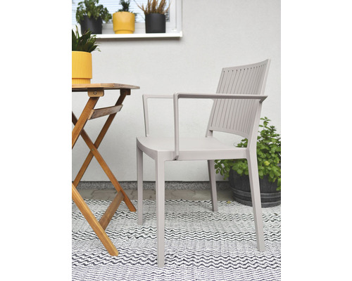 Záhradná scéna s kreslom, dreveným stolom a vzorovaným kobercom