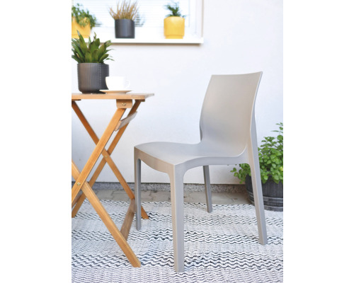 Scéna so sivou plastovou záhradnou stoličkou a dreveným stolom na balkóne