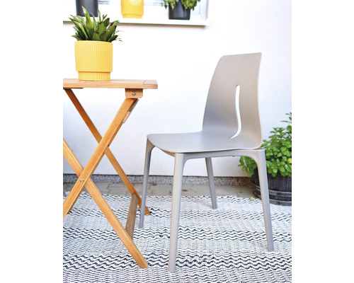 Záhradná scéna so skladacím stolom, záhradnou stoličkou a kvetináčmi na koberci