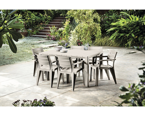 Štvorcový záhradný stôl s ôsmimi stoličkami v zelenej záhrade.