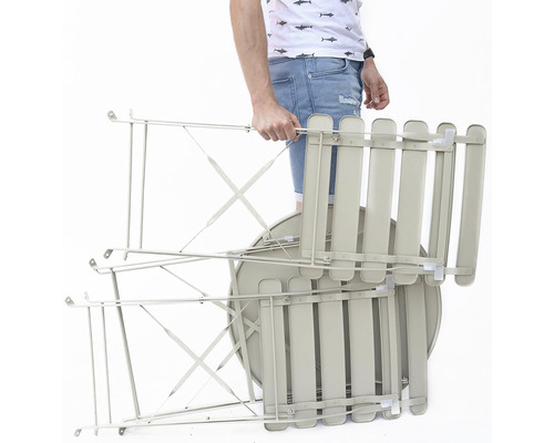 Zloženú záhradnú súpravu stola a stoličiek nesie osoba.