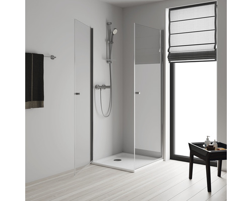 Sprchovací kút so sklenenými dverami, sprchová armatúra a držiak na uteráky vo svetlej kúpeľni