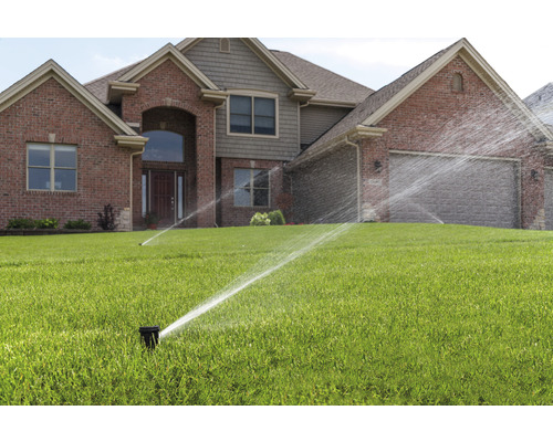 Zavlažovací systém s trávnikovými postrekovačmi pred domom.