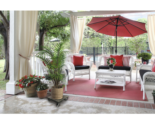 Terasa s bielym prúteným nábytkom, červeným slnečníkom a hrnkovými rastlinami