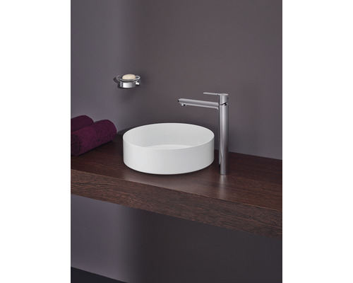 Kúpeľňové umývadlo s batériou, mydelničkou a uterákmi na drevenej polici.