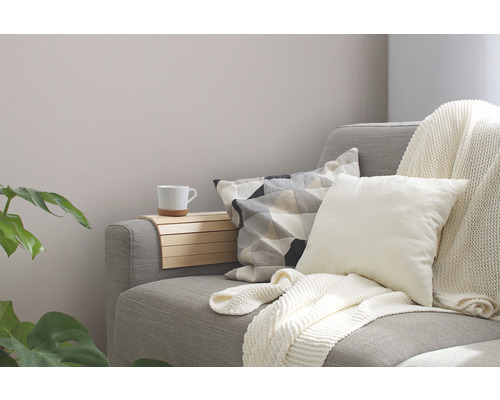 Útulná obývacia izba s pohovkou, vankúšmi, dekou a príručným stolíkom