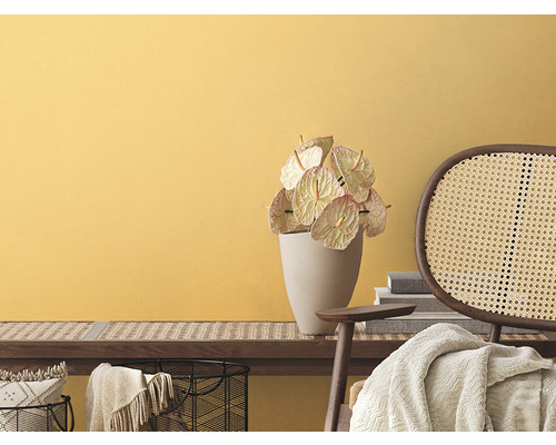 Obývacia izba so žltou stenou, lavica s ratanovou väzbou, antúrie vo váze a ratanová stolička