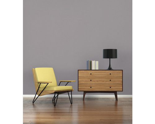 Obývacia izba s kreslom, komodou, lampou a knihami na drevenej podlahe