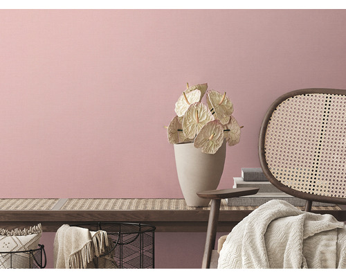 Svetlý interiér s kvetmi vo váze a ratanovým kreslom pred ružovou stenou