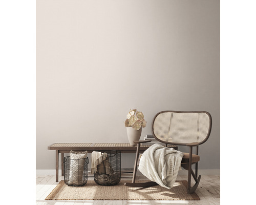 Obývacia izba s lavicou, prúteným hojdacím kreslom, košmi a dekoráciou na koberci.