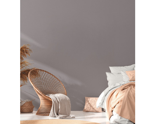 Svetlá miestnosť s ratanovým kreslom, posteľou a dekoráciou pre útulnú atmosféru.