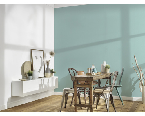 Jedáleň s dreveným stolom, stoličkami a nástennou policou s dekoráciami pred farebnou stenou