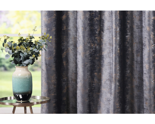 Dekoratívny záves s abstraktným vzorom vedľa vázy s kvetinami na stole.