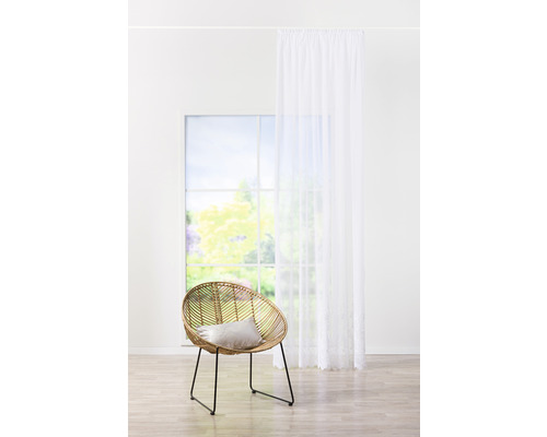 Svetlá miestnosť s ratanovým kreslom, vankúšom, oknom a závesom