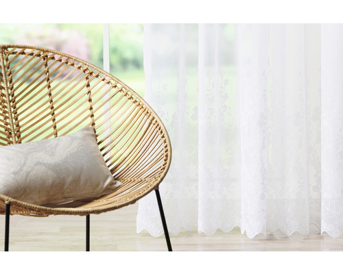Dekoratívne obytné prostredie s ratanovým kreslom, vankúšom a bielym závesom s kvetinovým vzorom