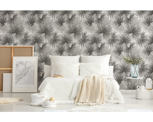 Spálňa so vzorovanou tapetou, posteľou a dekoratívnymi predmetmi pre útulné prostredie.