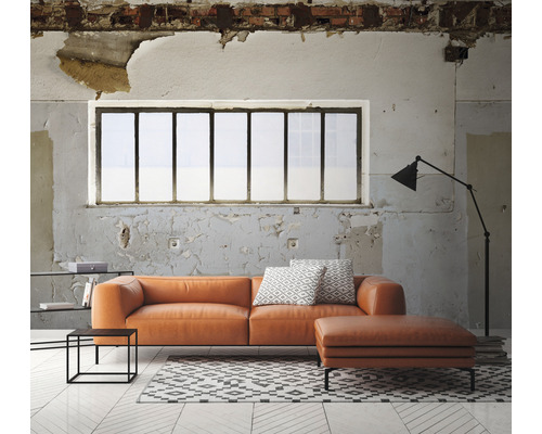 Obývacia izba s oranžovou koženou sedačkou, otomanom, kobercom a stojacou lampou pred oknom