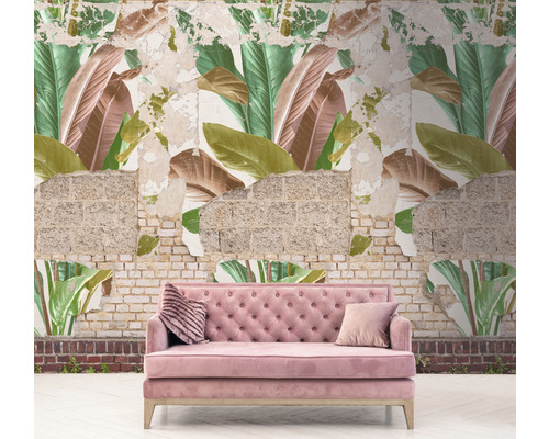Ružová pohovka pred stenou s tapetou s motívom listov a odhaleným murivom