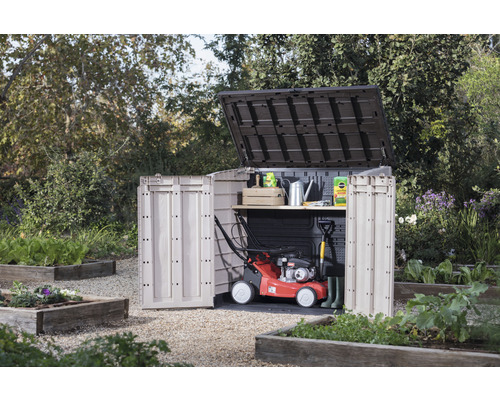 Záhradná scéna so záhradnou skriňou s otvorenými dverami, kosačkou na trávu a záhradným náradím