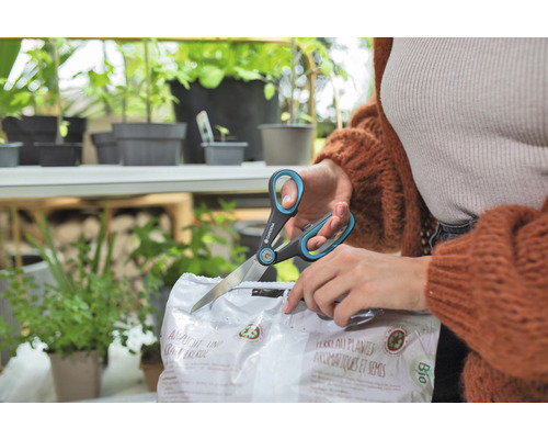 Osoba otvára balenie zeminy na výsev a bylinky nožnicami značky Gardena.