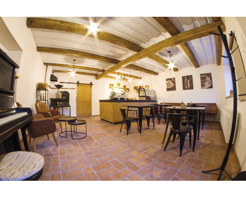 Interiér kaviarne so stolmi, stoličkami, barom, kávovarom a dekoráciami