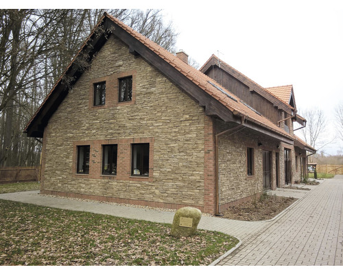 Pohľad na budovu s fasádou z kamenných obkladových pásov a škridlovou strechou