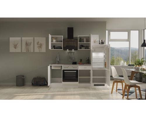 Svetlá kuchyňa s kuchynskými skrinkami, digestorom, sporákom, drezom a chladničkou.