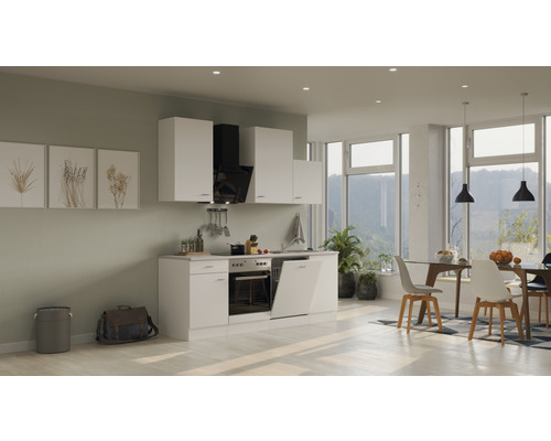 Svetlá vstavaná kuchyňa s bielymi skrinkami, odsávačom pár a jedálenským priestorom so stolom a stoličkami.