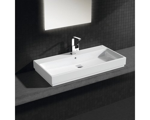 Obdĺžnikové keramické umývadlo s batériou a zrkadlom na tmavej stene