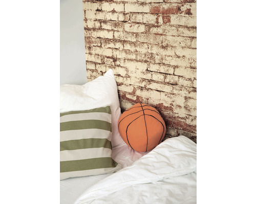 Dekoratívna spálňa s vankúšmi, prikrývkou a tapetou na stenu s tehlovým vzhľadom