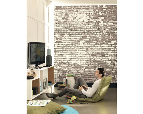 Obývacia izba s tehlovou stenou, televízorom a mužom hrajúcim videohru