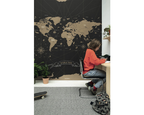 Izba s tapetou s mapou sveta, písacím stolom a dieťaťom, ktoré sa učí