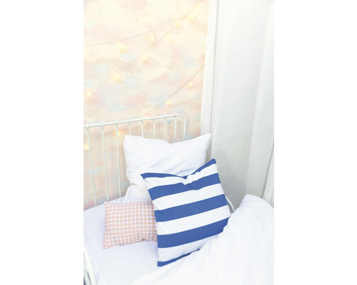 Posteľ s vankúšmi a svetelnou reťazou