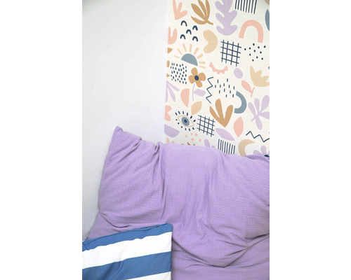 Stena s tapetou s abstraktným vzorom, fialový vankúš a pruhovaný vankúš