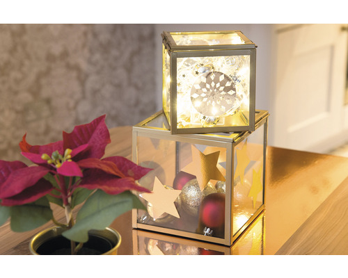 Dekoratívne sklenené krabice s vianočnými ozdobami a osvetlením na stole s vianočnou hviezdou.