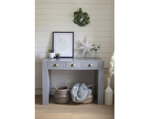 Sivý konzolový stolík s tromi zásuvkami, košíkmi a dekoráciami na drevenej podlahe