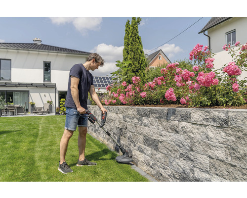 Muž používa vyžínač v záhrade.