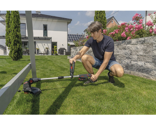 Muž montuje akumulátorový vyžínač na trávu v záhrade.