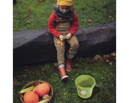 Scéna s dieťaťom, tekvicami v košíku a zeleným vedrom na trávniku