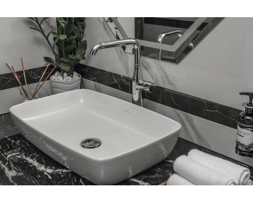 Umývadlo v kúpeľni s batériou, uteráky a dekorácia na mramorovom povrchu