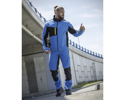 Muž v modrej pracovnej bunde a nohaviciach s palcom hore