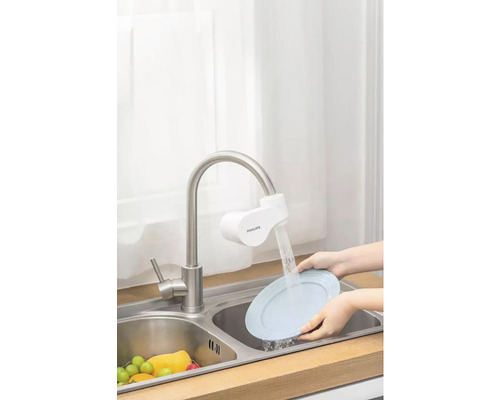 Scéna kuchynského drezu s vodovodným filtrom a osobou umývajúcou tanier