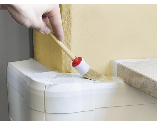 Osoba maľuje stenu okrúhlym štetcom