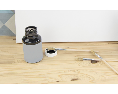 Vedro s farbou a štetcami na drevenom pozadí