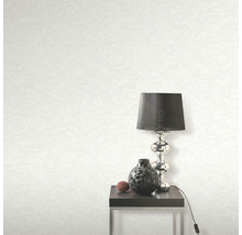 Svetlá tapeta s textúrou, stolná lampa, dekorácia a stolík v izbe.