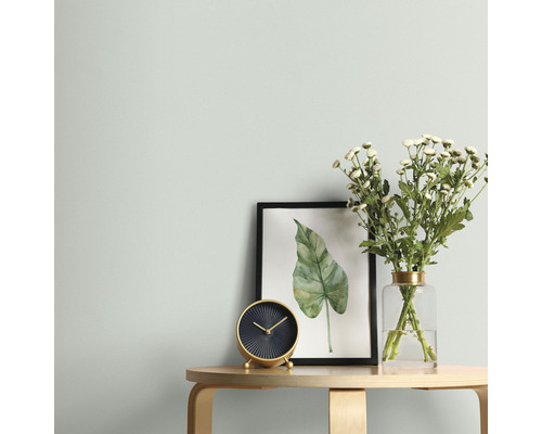 Obývacia izba so stolom, hodinami, kvetmi a zarámovaným obrazom na stene