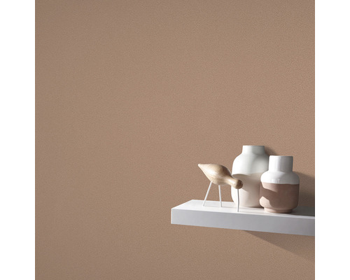 Detail steny s hrubou omietkou a dekoratívnymi predmetmi na poličke