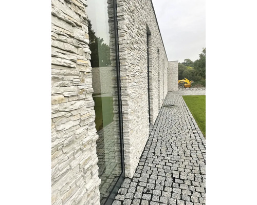 Exteriér modernej budovy s fasádou z prírodného kameňa a dláždenou cestou